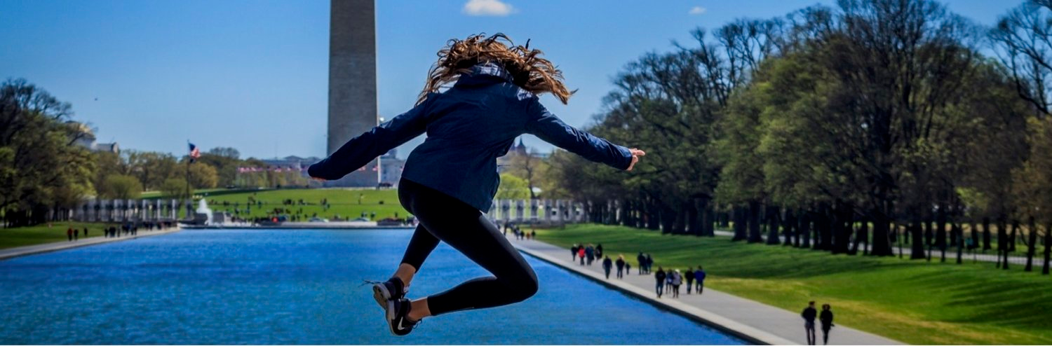 Photo shows a girl jumping in front of a WA monument.