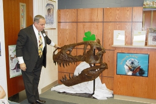 Larry James presents an elementary school with a replica of a dinosaur head. Click to enlarge