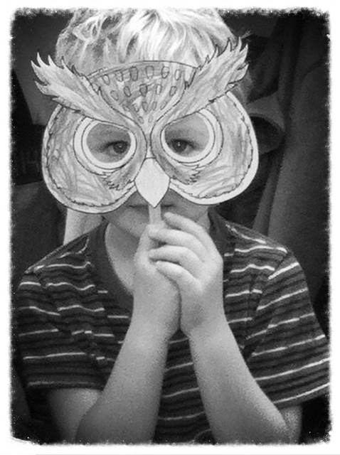 elementary student holding a mask over his face