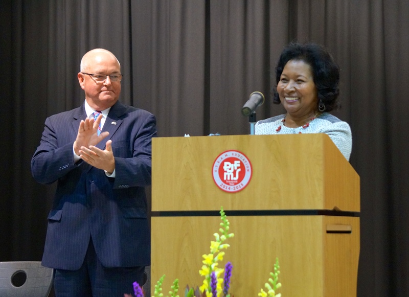 School Board Chairman Chuck Saylors looks on as Dr. Phinnize J. Fisher is greeted with warm applause at the dedication ceremony of the middle school named in her honor.