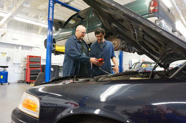 Auto Tech Instructor Scott Chandler and Timothy Ossman do an evaluation under the hood of the patrol car. 