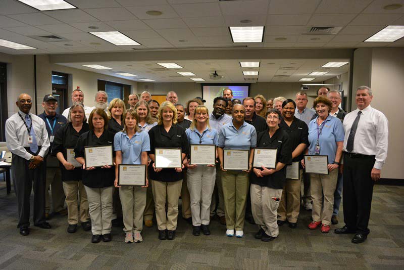 large group of operations managers and supervisors holding plaques