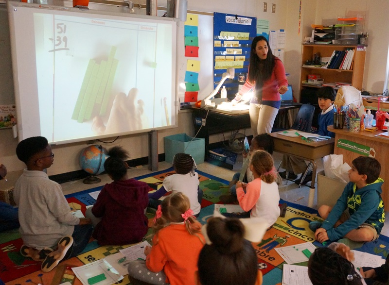 Female elementary teacher using overhead projector to teach lesson