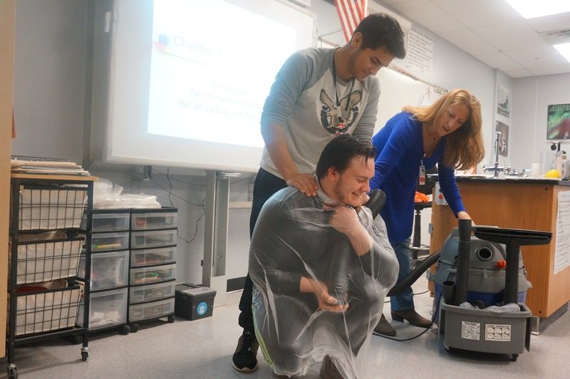 Beth Leavitt with two male students doing a vacuum experiment