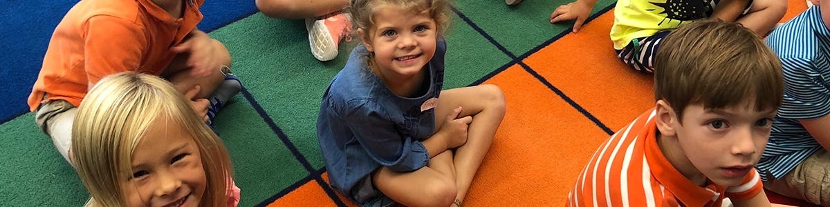 Elementary students sitting on floor smiling