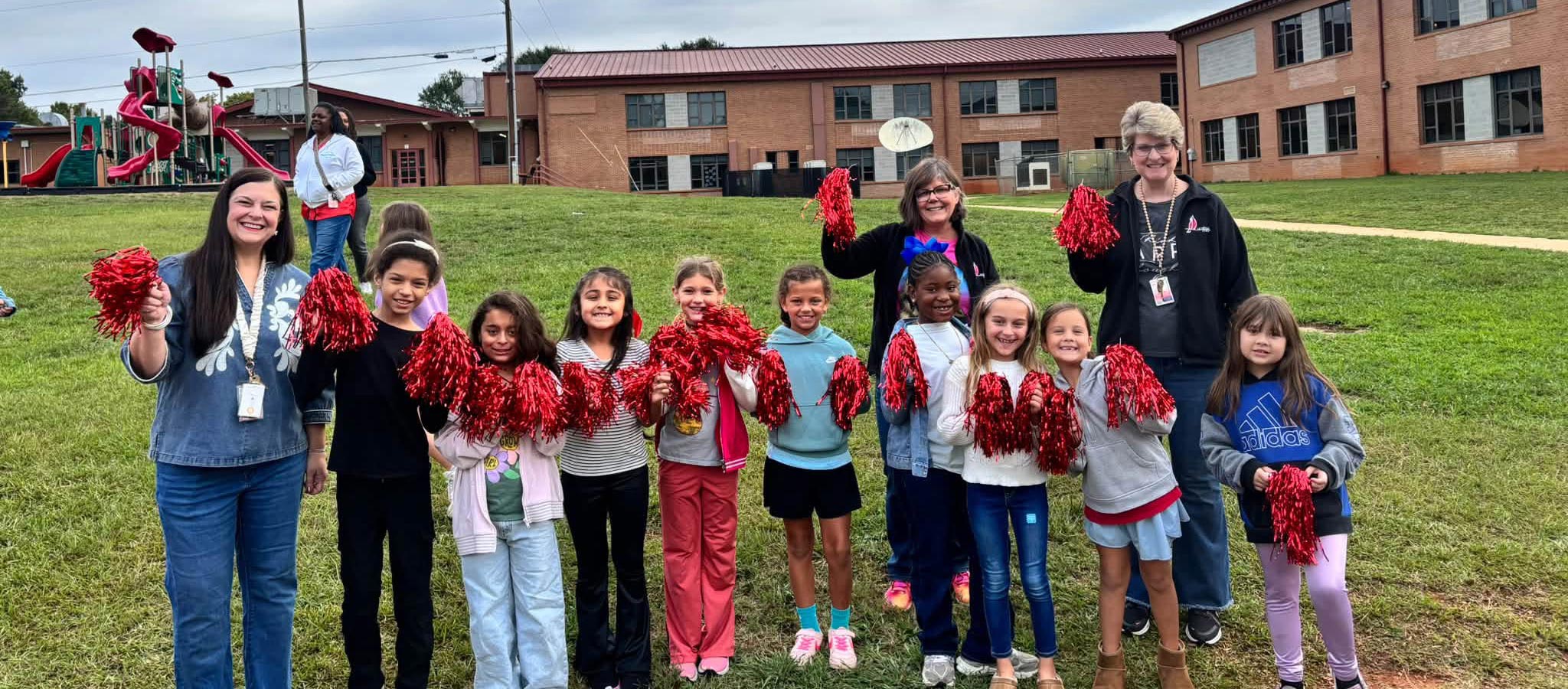 class of students and teachers with red pom poms