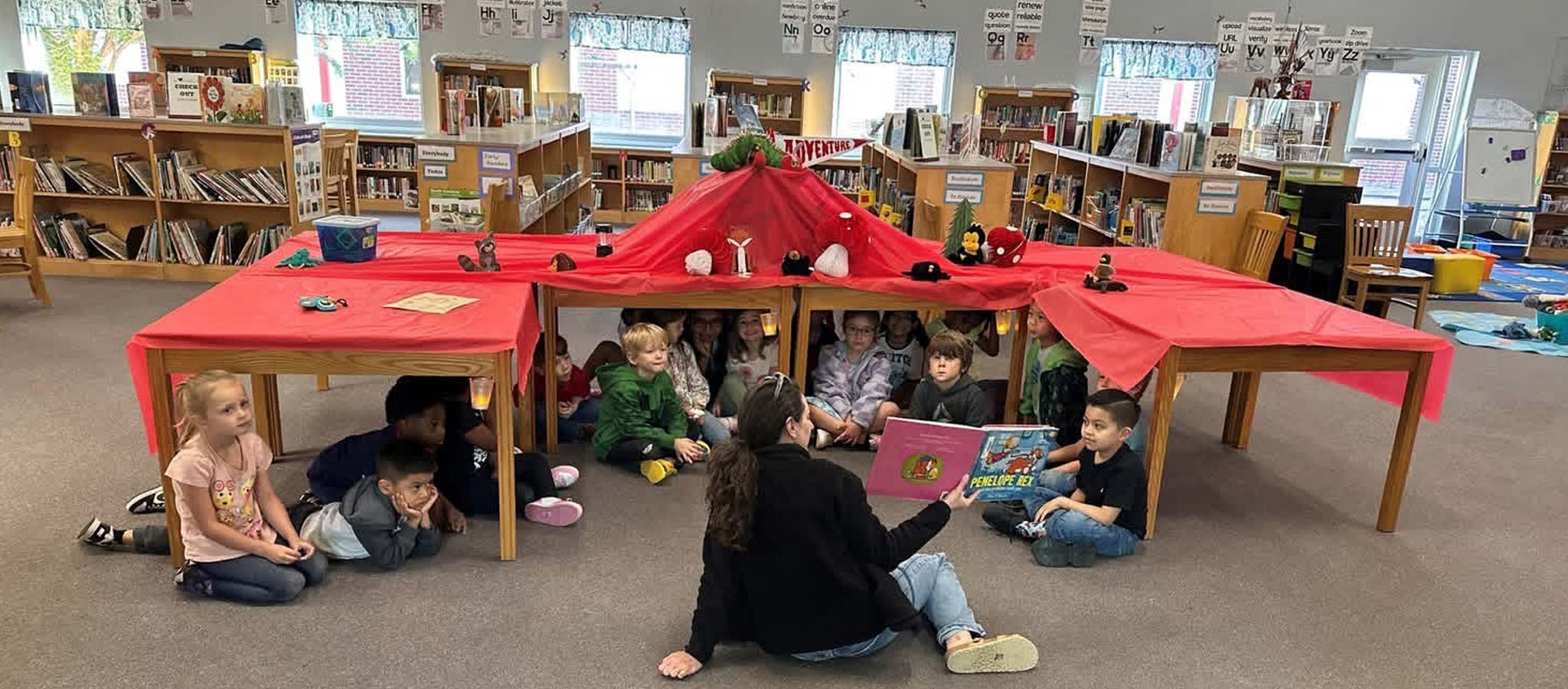 Teacher reading to a group of students in the media center