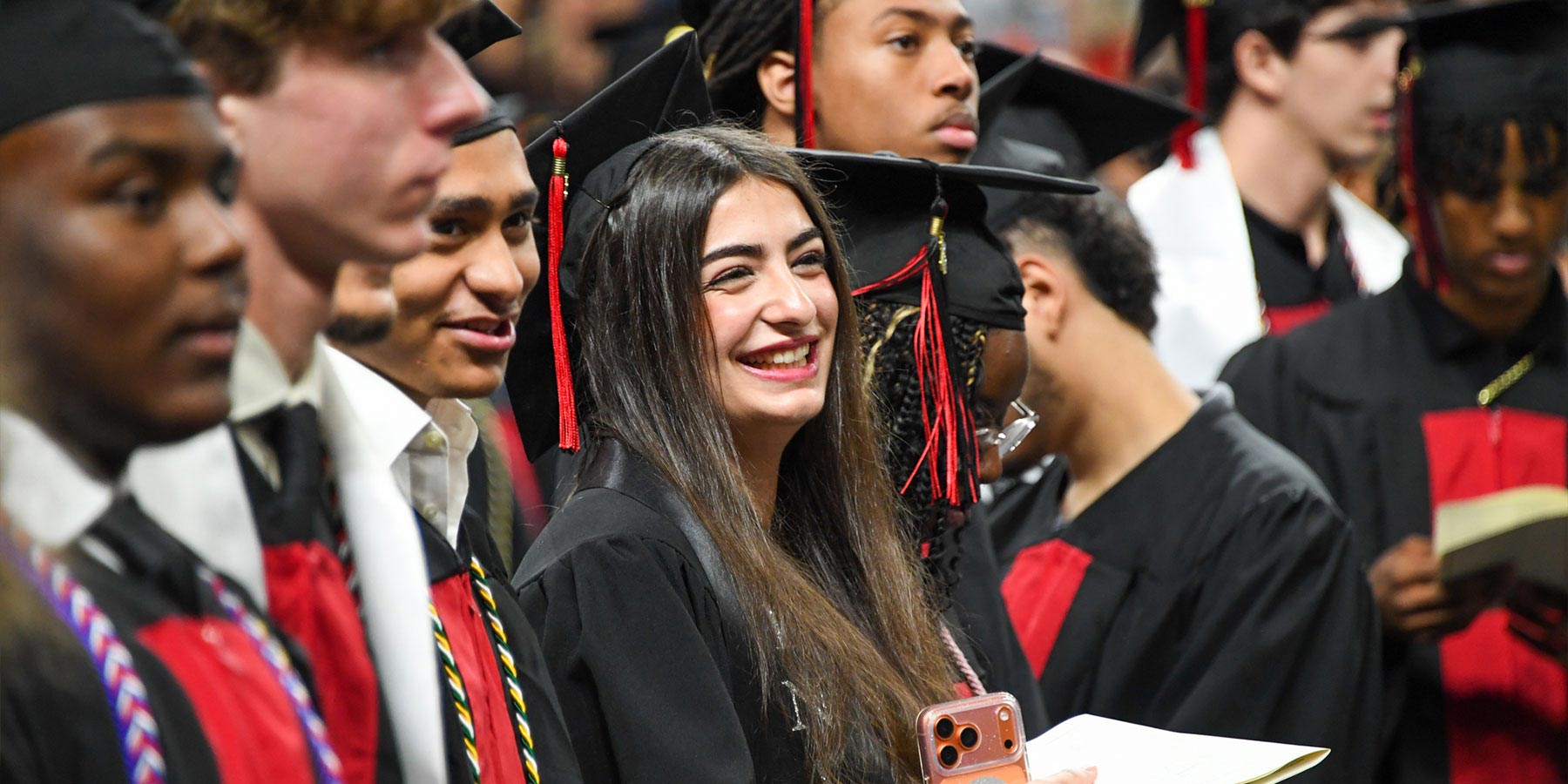 girl smiling among students in graduation regalia