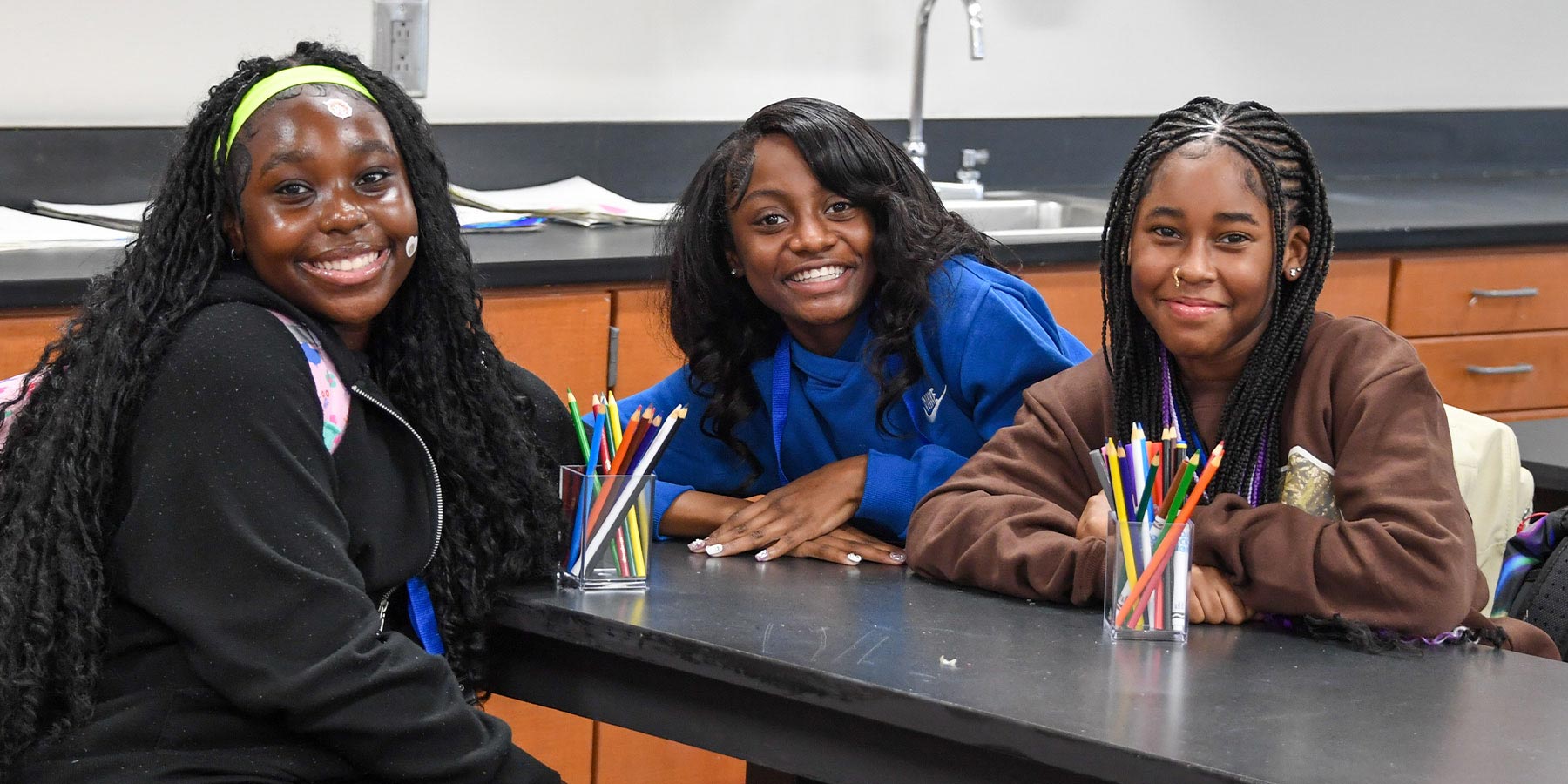 3 smiling girls sitting at a classroom table