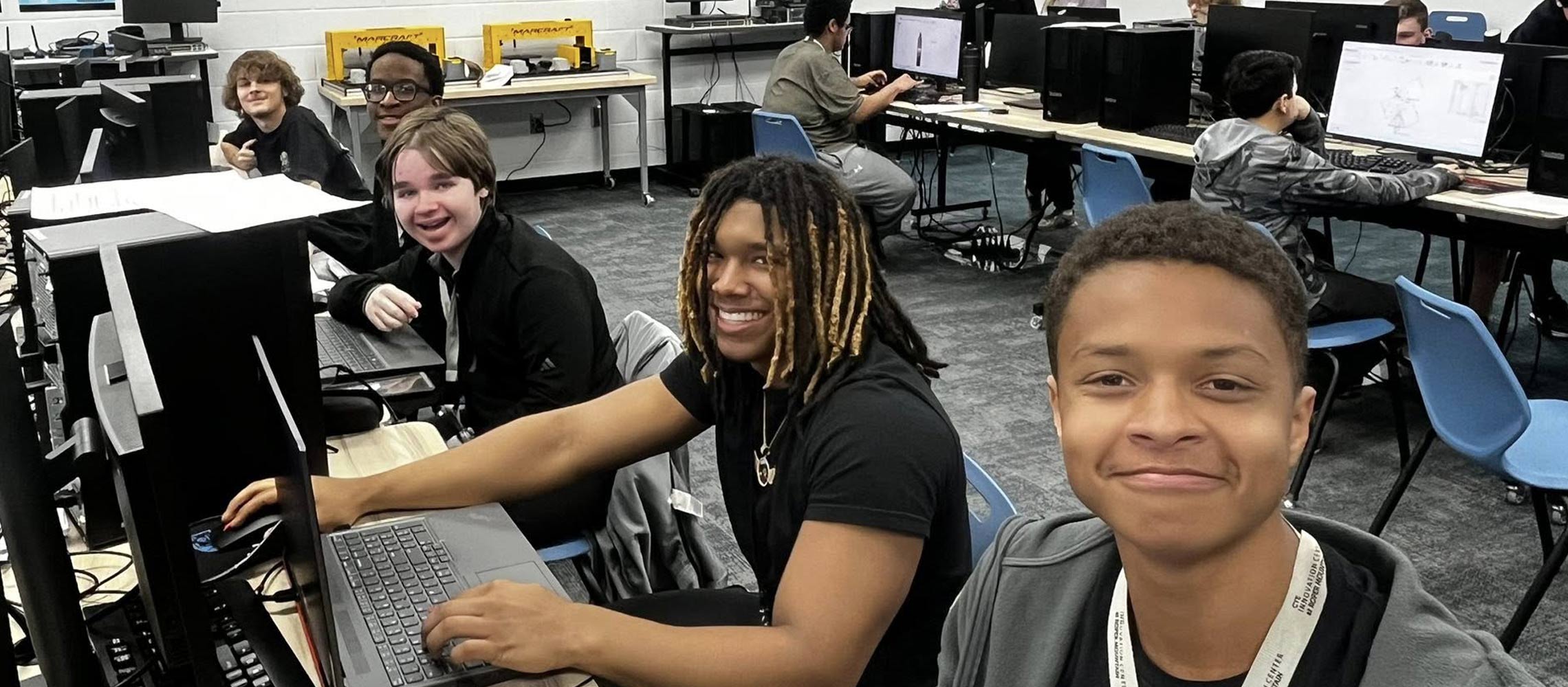 students smiling and working on computers