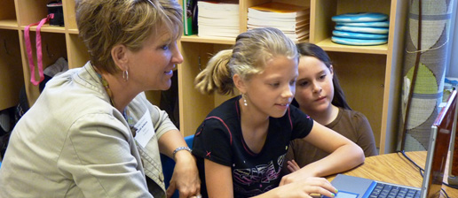 Teacher with an elementary student looking on computer
