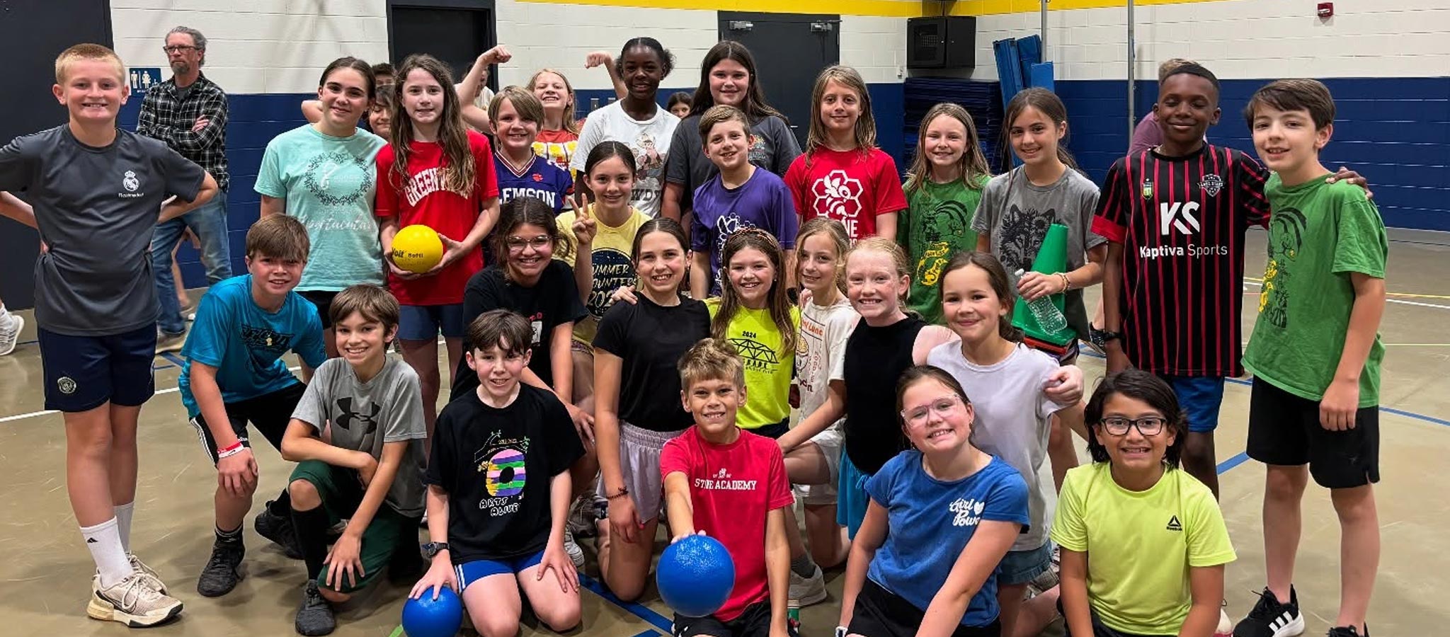 Class of students in gymnasium with volleyballs