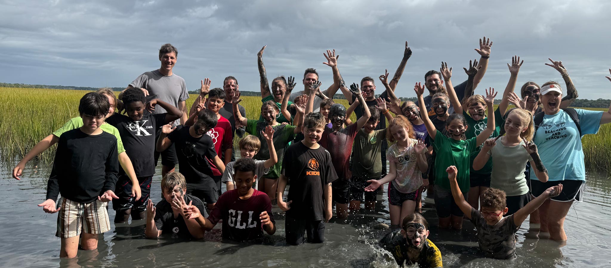 group of students with a teacher staning in knee-deep water near barrier islands