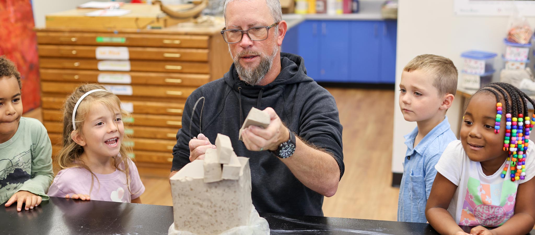 teacher with students builidng something with what appears to be clay