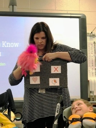 With the help of Speech Therapist Melissa Brothers, BeBo, the Washington Center communication puppet, is telling student friends to "wait" to find out where he was when he lost his voice.