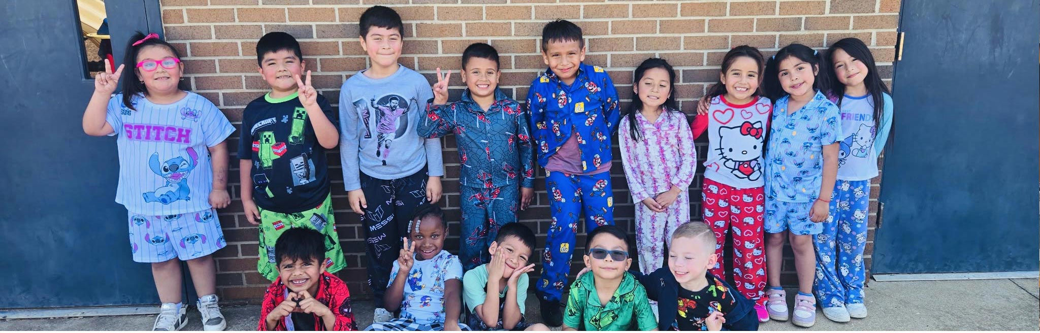 Group of happy elementary students outside in front of wall